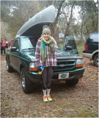 Canoe loaded on top of a car with a girl smiling.